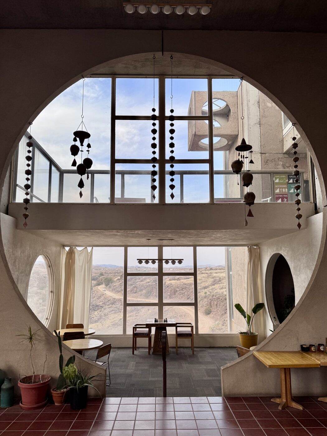 Ventana circular en Arcosanti con campanas colgantes y vista al desierto