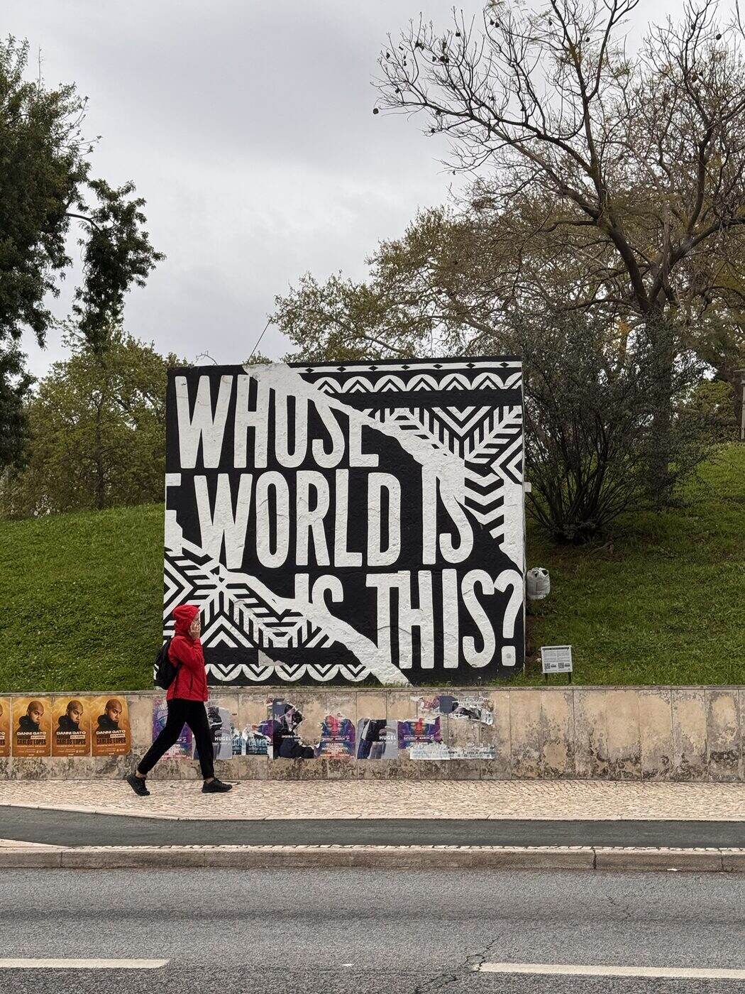 Mural “Whose world is this?” y un peatón con chaqueta roja